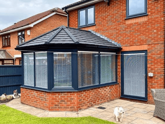 Grey conservatory with tiled roof on a red brick house